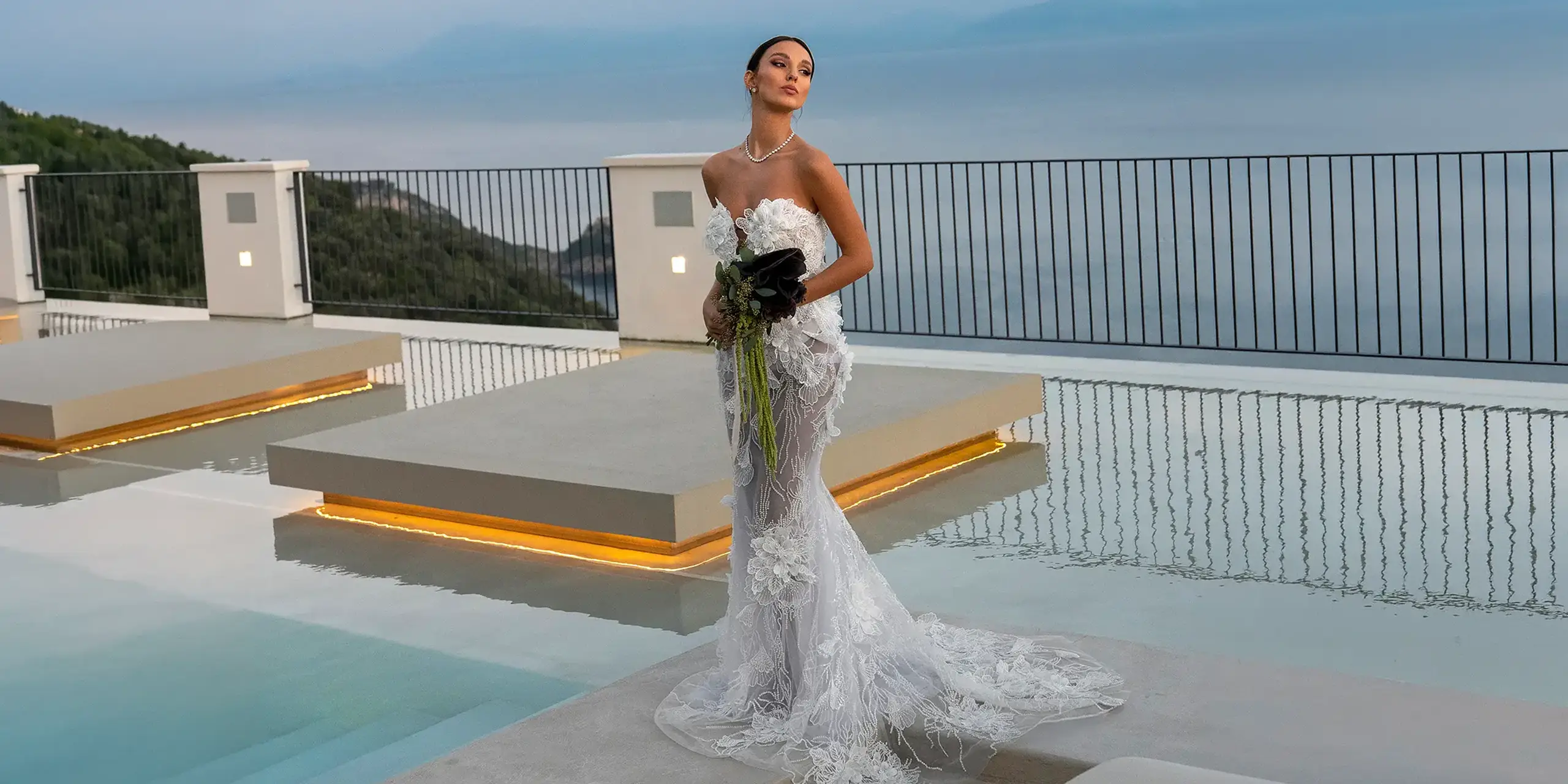 Sposa con bouquet sulla terrazza con piscina del Grand Hotel Furore, affacciata sul mare della Costiera Amalfitana, all'imbrunire
